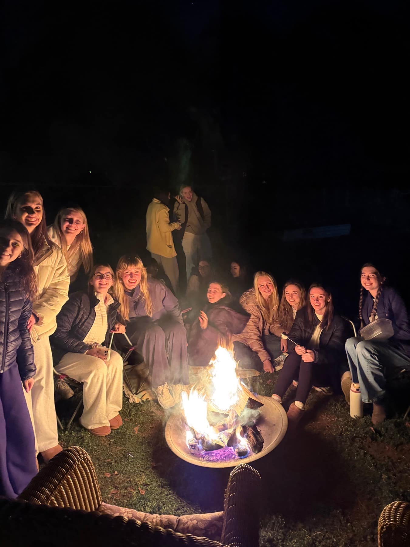 A large circle of RUF freshmen spending time together around the bonfire